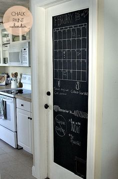 a chalkboard door is open to reveal the kitchen's white cabinets and appliances