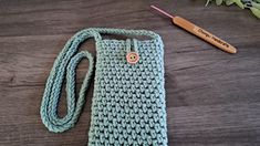 a crocheted cell phone case sitting on top of a table next to a knitting needle