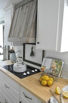 a kitchen with white cabinets and wooden counter tops, along with an oven hood over the stove