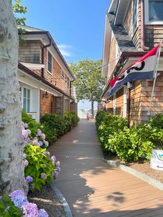 a wooden walkway between two buildings with flowers in the foreground and an american flag on top