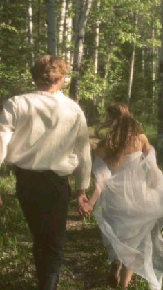 a man and woman are walking in the woods