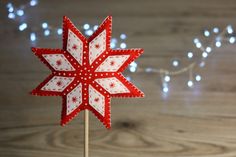 a red and white snowflake shaped cake topper on a wooden table with lights in the background