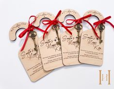 four wooden tags with red ribbon tied around them and two keys attached to each tag