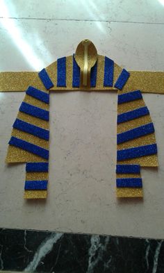 a gold and blue decoration on a marble floor with a spoon in the shape of an egyptian scarves