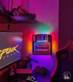 a computer desk topped with a monitor and keyboard next to a neon lit wallpaper