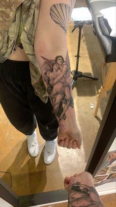 a man with tattoos on his arm holding the hand of another person's leg