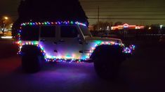 a jeep decorated with christmas lights in the dark