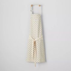 an apron hanging on a white wall with black dots and a wooden hanger attached to it