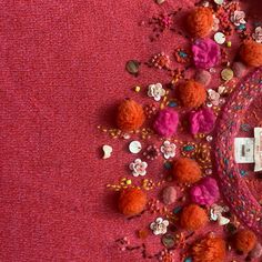 a pile of colorful pom poms on top of a red carpet next to a cell phone