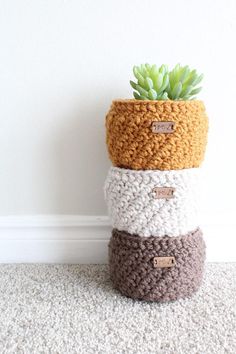 four crocheted pots are stacked on top of each other and one has a succulent plant in it