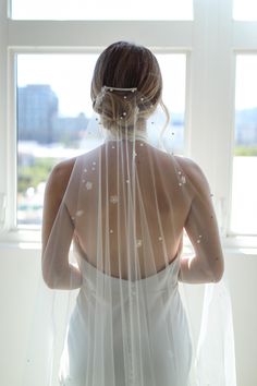 the back of a bride's dress is covered with white flowers and veils