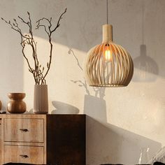 a lamp hanging from the side of a wall next to a dresser and vases