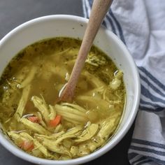 a white bowl filled with soup on top of a table next to a wooden spoon