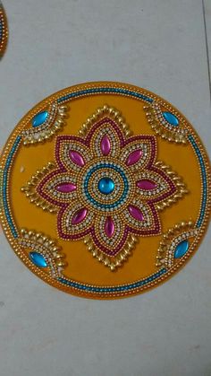 an intricately designed yellow plate with blue and pink beads on the edges, sitting on a white surface