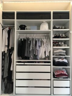 an organized closet with white drawers and clothes hanging on the shelves, along with several pairs of shoes