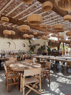 an indoor dining area with tables, chairs and hanging baskets on the ceiling above them