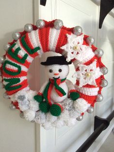 a knitted wreath with a snowman on it hanging from the front door handle