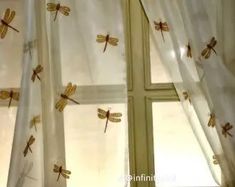 the window is decorated with dragonflys on white drapes and sheered curtains