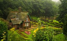 the garden is surrounded by lush green trees and bushes, with a small house in the middle