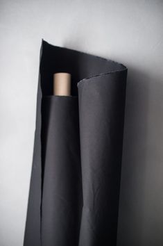 two tall black vases sitting next to each other on top of a wall in front of a white wall