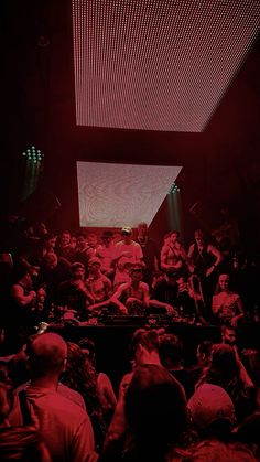 a large group of people in a room with red lights on the ceiling and floor