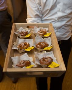 a person holding a wooden tray filled with donuts