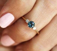 a woman's hand holding a ring with two blue and white stones on it