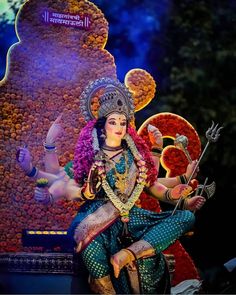 a statue of a woman sitting on top of a table next to a giant flower arrangement