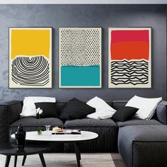 three paintings hang on the wall above a couch in a living room with black furniture