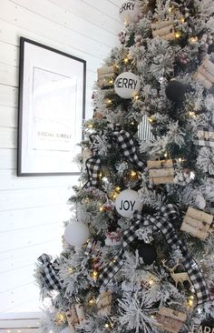 a christmas tree decorated with black and white plaid ribbon, wooden tags, and ornaments