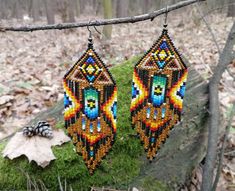 beaded earrings hanging from a tree branch in the woods