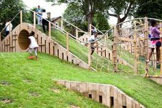 children playing on wooden play structures in the park, with people climbing up and down them