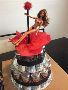 a barbie doll sitting on top of a stack of cans