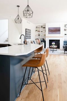 a kitchen with an island and bar stools next to the counter top in front of a fireplace