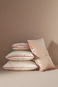 four pillows stacked on top of each other in front of a brown wall with pink trim