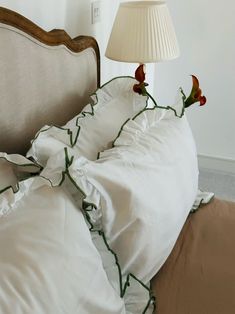 a bed with white sheets and green trim around the headboard has a lamp on it