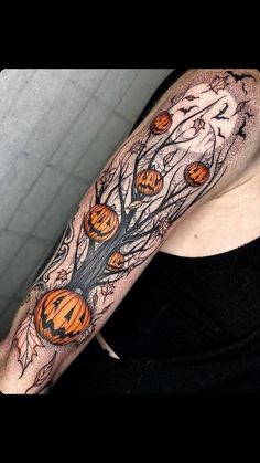 a woman's arm with pumpkins on it and a tree in the background