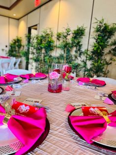 the table is set with pink napkins and place settings