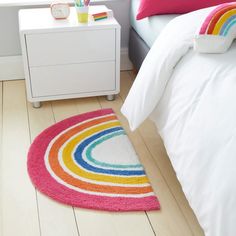 a bedroom with a rainbow rug on the floor next to a white dresser and bed