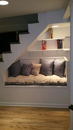 a window seat in the corner of a room with bookshelves and pillows on it