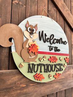 a sign that says welcome to the nuthouse with a squirrel holding an acorn