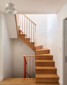 there is a stair case next to the door in this room with white walls and wood floors