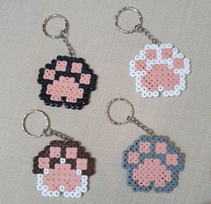 four pixel keychains are shown on a white surface with pink and blue designs