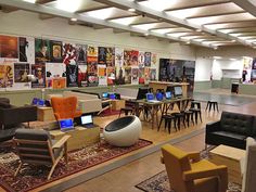 a large room filled with lots of tables and chairs next to laptops on desks