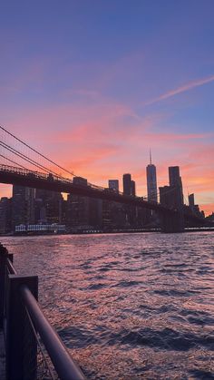 the sun is setting over the city skyline as it reflects in the water and bridge