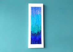 a blue and green painting hanging on the wall