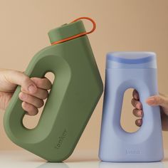 a hand holding a bottle next to a green and blue container