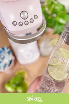 a person is holding a bottle with some limes in it next to a blender