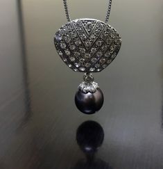 DeKara Designs Art Deco Inspired Pearl Diamond Drop Necklace. Metal- 14K White Gold, .583. Stones- 1 Tahitian Black Pearl 11 MM, 55 Round Diamonds G-H Color VS2-SI1 Clarity 1.80 Carats. Pendant measures 1.4 inches long, and 0.92 inches wide. An elegant handmade Tahitian black diamond necklace made in 14k white gold. There is a beautiful black Tahitian pearl with six round pave set diamonds and a bezel set round diamond dangling off a pave diamond encrusted piece to form a beautiful drop necklace Elegant Necklace With Large Oval Pendant, Formal Oval Pendant Large Necklace, Formal Oval Pendant Necklace With Large Pendant, Formal Necklace With Large Oval Pendant, Art Deco Pendant Necklace For Formal Occasions, Exquisite Formal Necklace With Large Pendant, Elegant Black Pearl Necklace For Evening, Elegant Oval Necklace For Evening, Exquisite Evening Necklace With Pearl Pendant