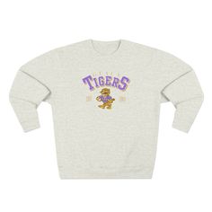 Gear up for chilly game days and tailgating with this stylish LSU Geaux Tigers Sweatshirt! Featuring a retro tiger design, it's the perfect blend of comfort and fashion for dedicated fans. This cute women's game day apparel is a must-have for every LSU supporter looking to showcase their team spirit. Shop now to ensure you stay warm and trendy while cheering on the Tigers this season! Featuring a 3-end fleece fabric, it has a real tight-knit construction giving it better quality and durability. It's not only beautiful but also comfy and soft to the touch with the best in its class and under 5% shrinkage. *Key Features* .: 80% cotton, 20% polyester  .: Medium-heavy fabric (8.25 oz /yd² (280 g/m .: Regular fit .: Tear away label .: Runs true to size Throwback Long Sleeve T-shirt For College, College Throwback Style Sweatshirt With Screen Print, Fall Throwback T-shirt With Letter Print, Fall Throwback Letter Print T-shirt, Retro Long Sleeve Pre-shrunk Sweatshirt, Throwback Long Sleeve Tops With Letter Print, Crew Neck Mascot Top For Fan Gear, Mascot Crew Neck Top For Fan Gear, Retro Sweatshirt For Game Day, Sports Season